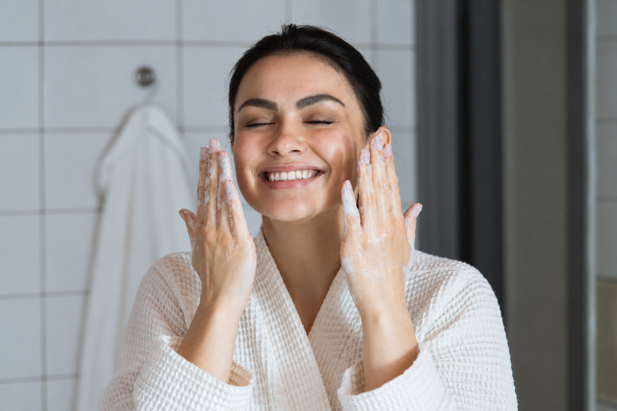 Woman massaging foaming face wash onto her cheeks, illustrating a cleansing routine for oily, acne-prone skin.